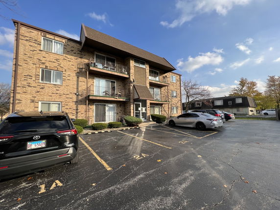 Front view of a three-story apartment building with balconies.