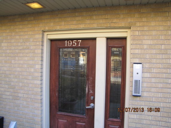 Front view of a building entrance with a glass and wood door, labeled with the number 1957.