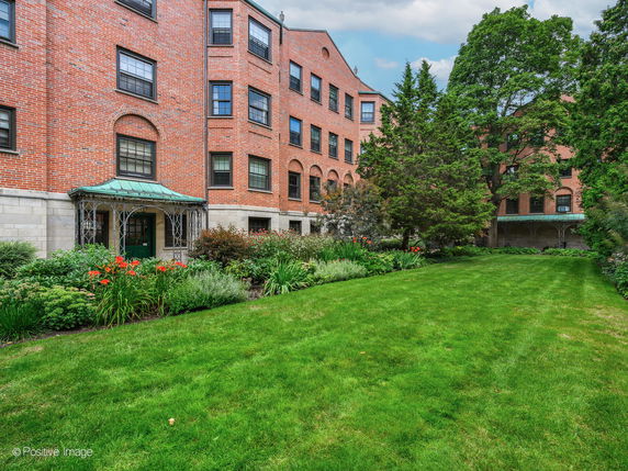 Front view of a multi-story brick building with arched windows and a green metal awning.
