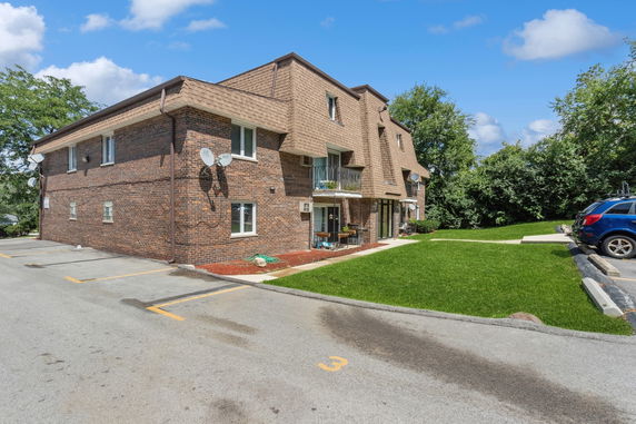Front view of a two-story brick building with balconies and parking area.
