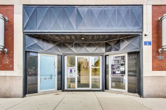 Front view of a commercial building entrance with glass doors and a geometric facade.