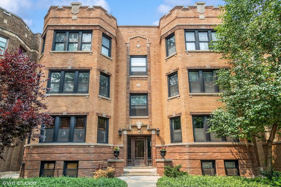 Front view of a multi-story brick apartment building with multiple windows.