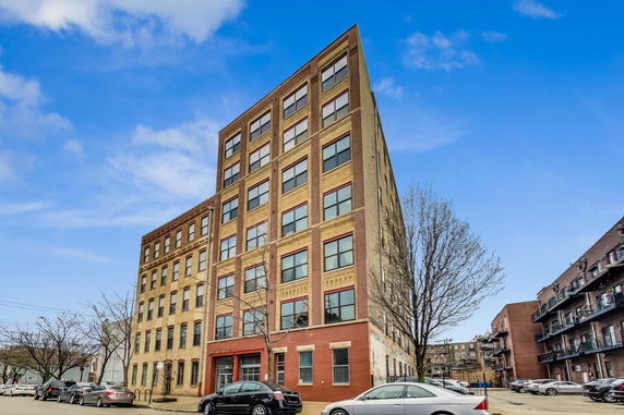 Front view of a multi-story building with a pointed corner.