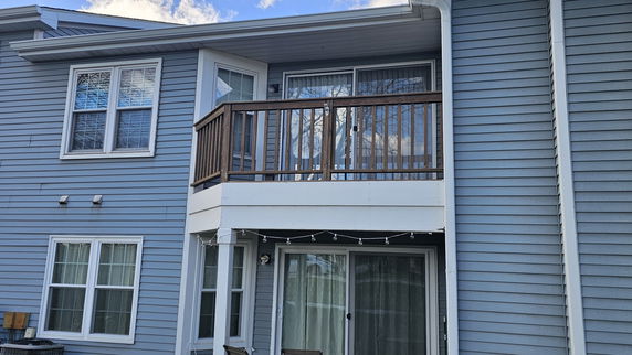Front view of a two-story house with a balcony and sliding glass doors.