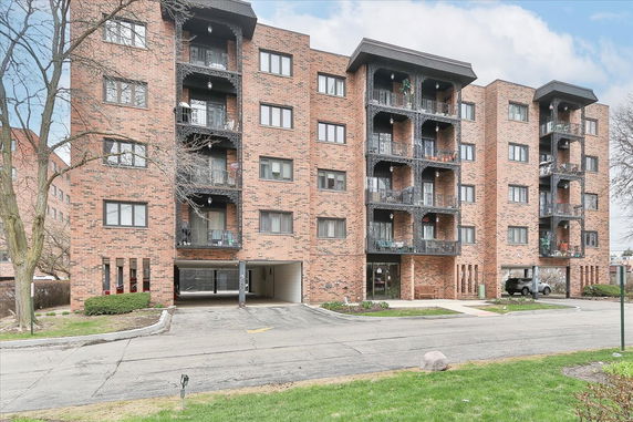 Front view of a multi-story brick apartment building with balconies.