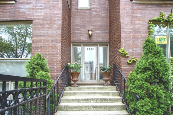 Front view of a brick house with stairs leading to a main entrance.
