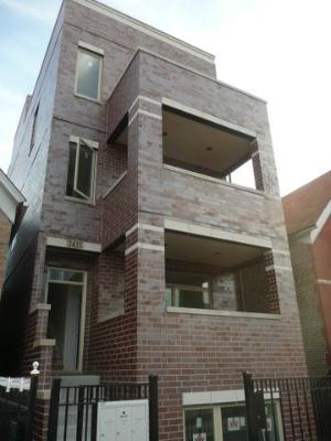 Front view of a three-story brick building with multiple balconies.