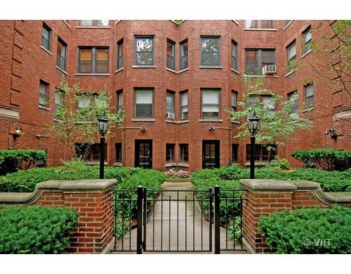 Front view of a brick apartment building with a gated entrance and landscaped courtyard.