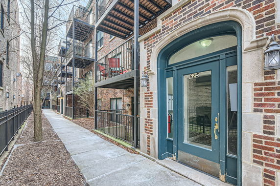 Front view of a multi-story brick apartment building with balconies.
