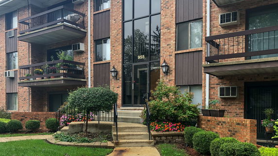 Front view of a multi-story brick residential building with balconies.