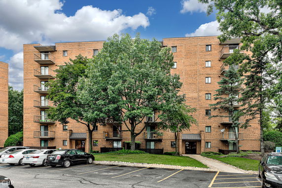 Front view of a multi-story brick apartment building with balconies.
