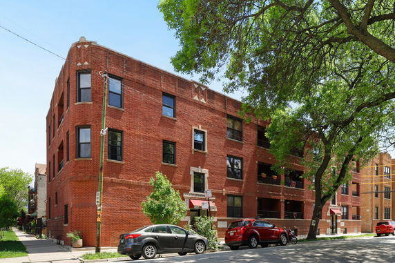 Front view of a multi-story red brick building with multiple windows and balconies.