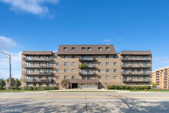 Front view of a multi-story apartment building with a brown brick exterior and balconies.