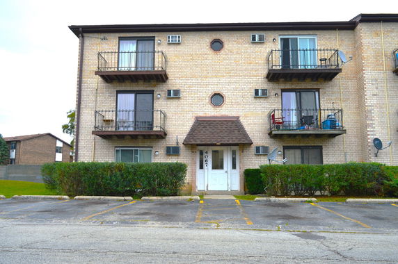 Front view of a brick apartment building with balconies and a central entrance.