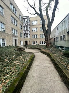 Front view of a multi-story residential building with a pathway leading to the entrance.