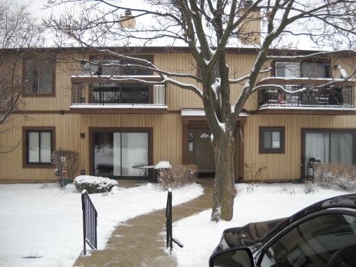Front view of a two-story house with beige siding and balconies, covered in snow.