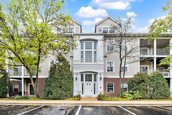 Front view of a three-story residential building with balconies and large windows.