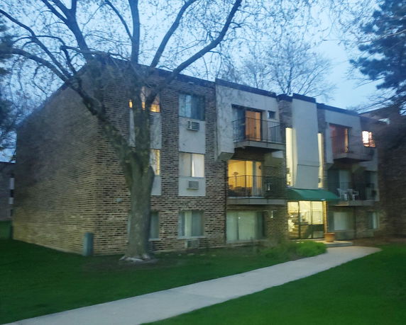 Front view of a multi-story apartment building with brick facade and balconies.