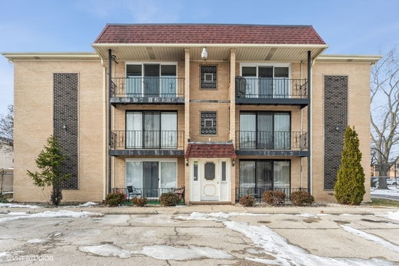 Front view of a three-story apartment building with balconies and a central entrance.