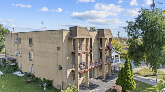 Front view of a three-story brick apartment building with balconies.