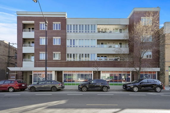Front view of a multi-story building with brick facade and large windows.