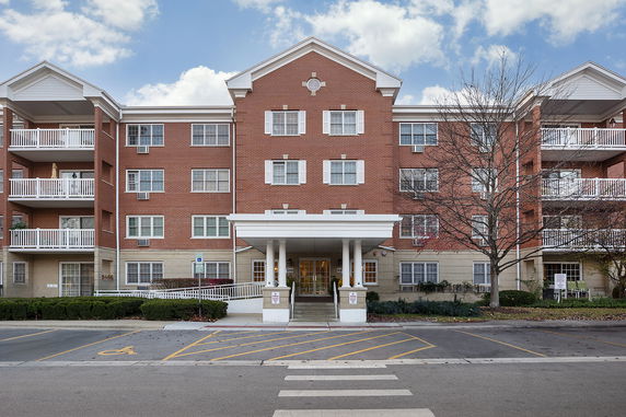 Front view of a multi-story brick building with balconies and a covered entrance.