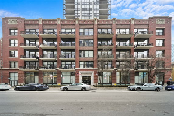 Front view of a multi-story brick apartment building with balconies.