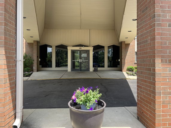 Front view of a building entrance with a covered walkway and large glass doors.
