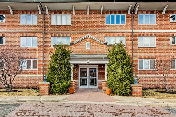 Front view of a multi-story brick building with entrance and symmetrical windows.