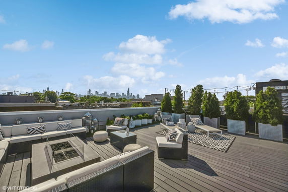 Spacious rooftop patio with seating and city skyline view.