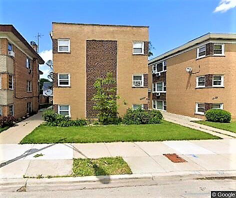 Front view of a multi-story brick apartment building with rectangular windows.