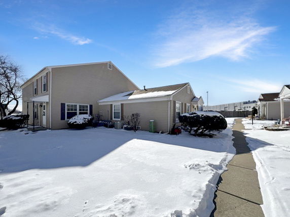 Front view of a two-story house with sloped roofs and a snow-covered driveway.