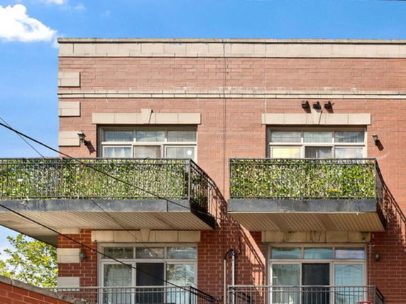 Front view of a two-story brick building with balcony railings.