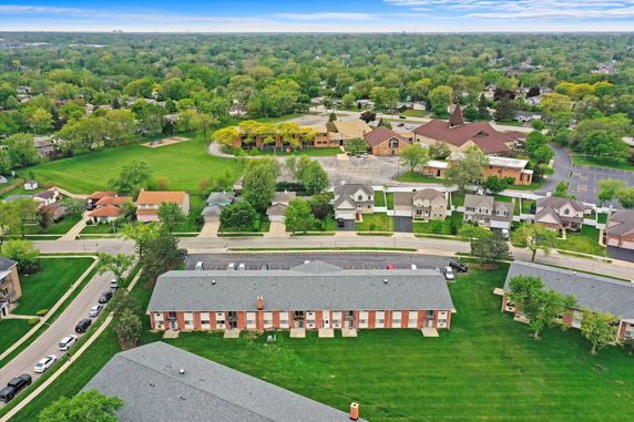 Aerial view showing residential buildings and a surrounding green area.