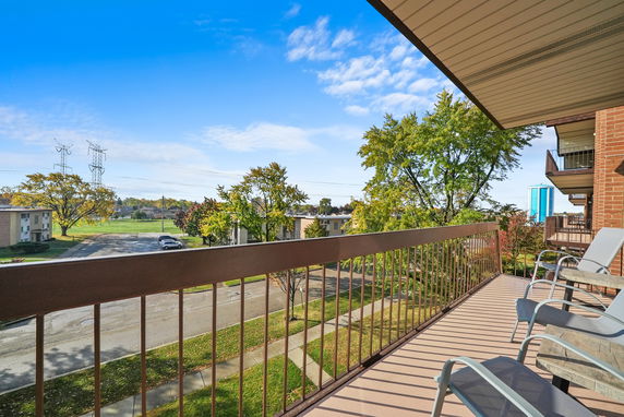 View from a balcony overlooking a neighborhood with trees and buildings.