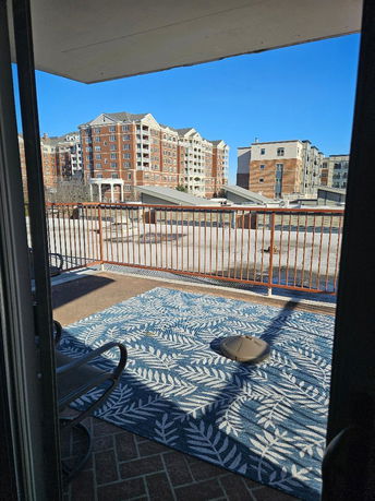 View of surrounding apartment buildings from a balcony with a rug and seating.