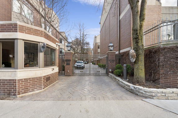 Front view of a building with a brick security booth and a gated entrance.
