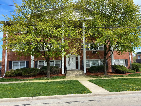 Front view of a two-story brick building with columns and windows.