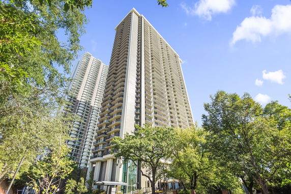 View of a tall residential building with multiple balconies set against a clear blue sky.