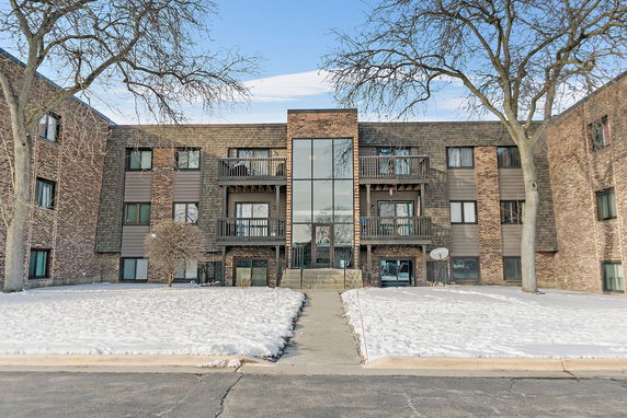 Front view of a multi-story brick apartment building with balconies.