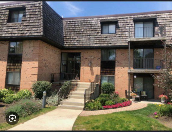Front view of a multi-story brick apartment building with balconies.
