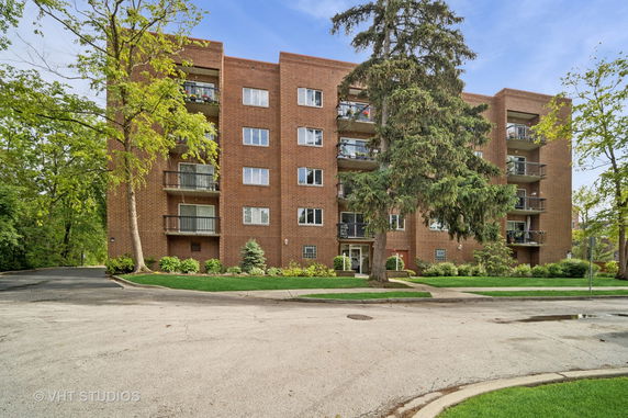 Front view of a multi-story brick apartment building with balconies.