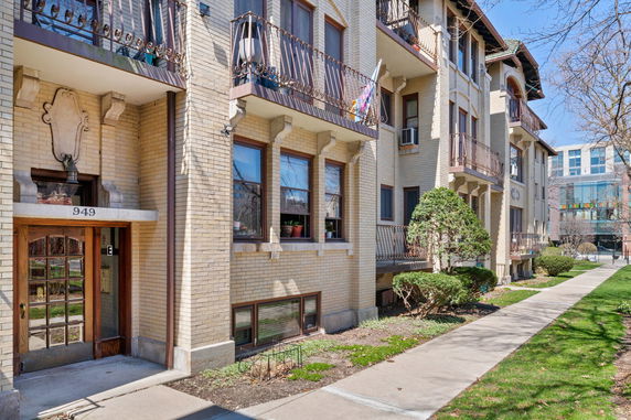 Front view of a multi-story residential building with balconies and a wooden entrance door.