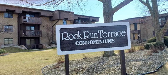 Front view of a condominium complex with a prominent sign reading 'Rock Run Terrace Condominiums'.