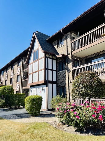 Front view of a multi-story building with balconies and Tudor-style architecture.