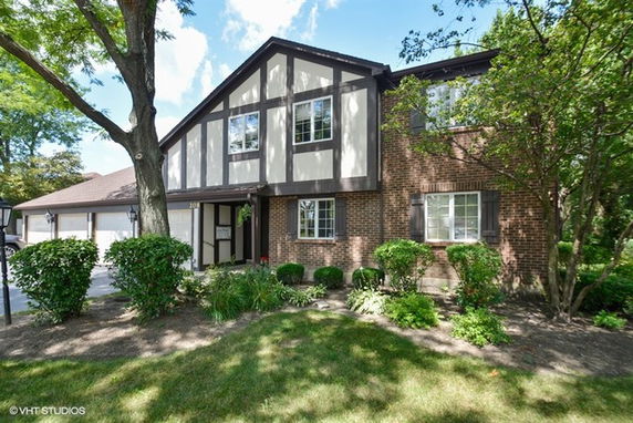 Front view of a two-story house with brick and wood paneling exterior.