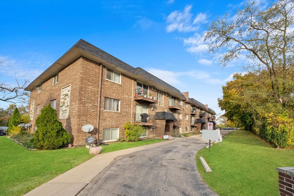 Front view of a multi-story brick apartment building with balconies.