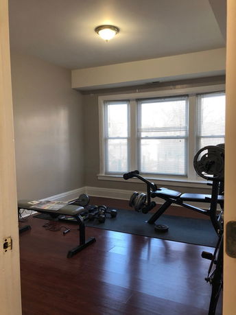Room with exercise equipment, including weights and a bench.