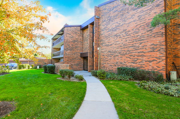 Front view of a brick multi-story residential building with balconies.