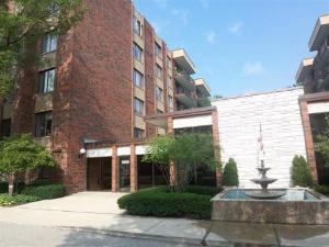 Front view of a multi-story brick building with a fountain at the entrance.